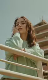 a woman is leaning on a rail outside