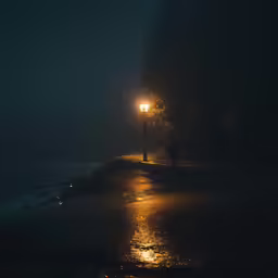 an area at night with a person walking on a pathway under an umbrella