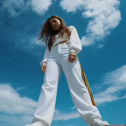 a woman in white jumpsuits standing on top of rock