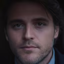 a man with dark hair wearing a suit and tie
