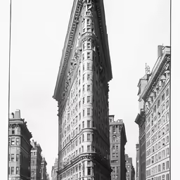 flat iron building, with an ornate sign, in the city