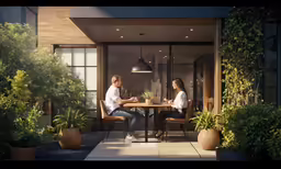 two people sitting at a table next to plants