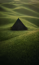 a lone tent in a grassy field under a setting sun
