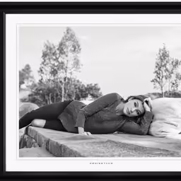 a woman laying on a stone wall in black and white