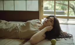 a young woman lays on a bed with her legs crossed while the apple sits beside her