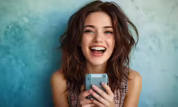 a woman smiling while looking at her cell phone