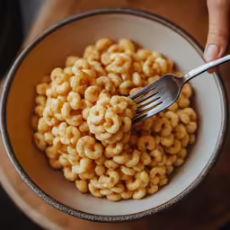 a person holding a fork in a bowl filled with cereal