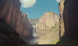 a man standing next to a waterfall near large mountains