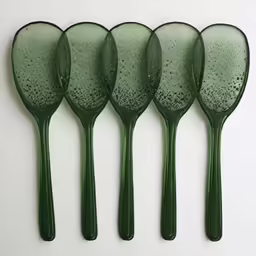 four green spoons that are sitting on a table