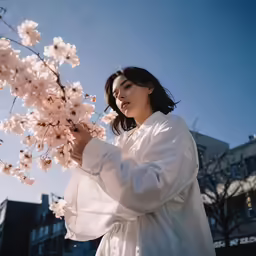 a woman is standing by a flower and looking at it