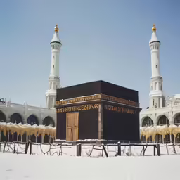 a small mosque stands in the snow near two big white towers