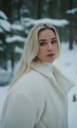a blond haired woman in white standing in the snow