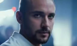 a man in white shirt and short undercut looking intently