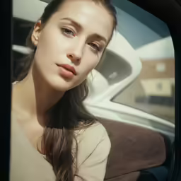 a woman in beige shirt with long hair looking out window