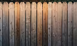 a wooden fence that is next to some shrubbery