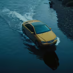 a yellow car is driving through water next to a hill