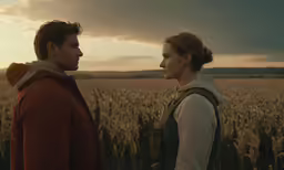 two people stand in a wheat field facing each other