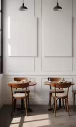 two small round tables and wooden chairs in front of the wall