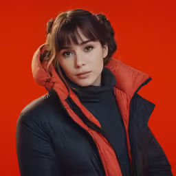 young female posing for photograph in an orange background