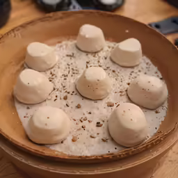 some marshmallows in a brown dish next to a bottle