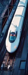a bullet train traveling down tracks next to a building