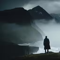 a man looks over the ocean while standing in the fog