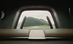 the back seat of a vehicle with mountains in the distance