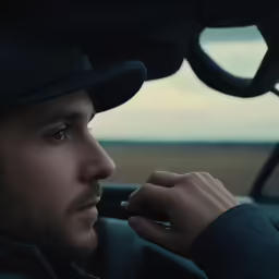 the man in the car is wearing a black hat