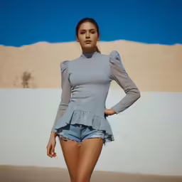 a woman in short jean shorts posing by a beach