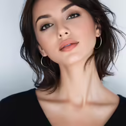 the model poses for the picture wearing gold hoop earrings