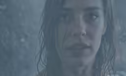 a woman with very dark eyes stares to the side in the rain