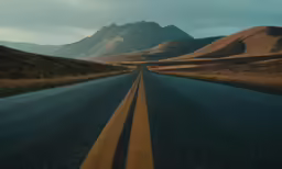 a long highway on a road with hills in the background