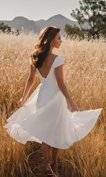 young beautiful woman in a short white dress walking through the field