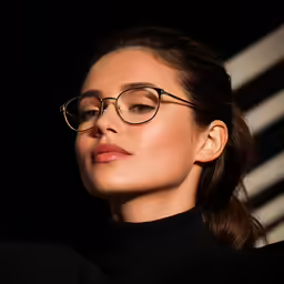 woman in black sweater with gold rimmed glasses