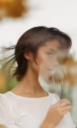 a woman wearing a white dress is blowing her hair