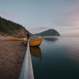 two small yellow boats tied to the side of the lake