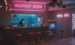 the front desk of a small bar with neon signs