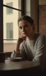 a woman sitting in front of a window at a table