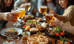 people raising glasses in celebration at wooden table