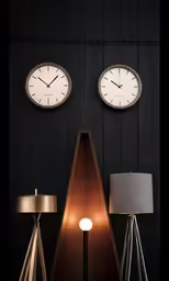two clocks on the wall between lamp and lamp