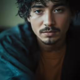 a man with curly hair and a beard looking directly at the camera