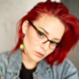a young woman with red hair, green eyes and yellow nose piercings