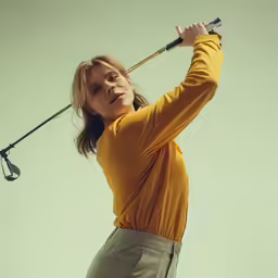a young woman holding a golf club in her hands
