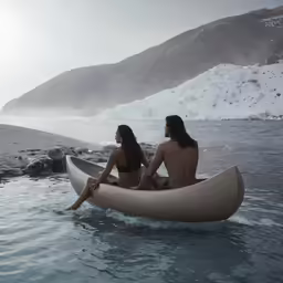two people sitting in a boat next to some snow