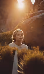 a woman standing in a grassy field with the sun going down