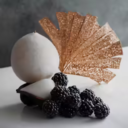 a white and gold umbrella sitting next to blackberries