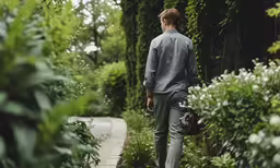 a man is walking down the path carrying a handbag