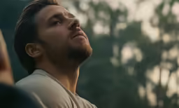 a man is staring ahead in front of trees