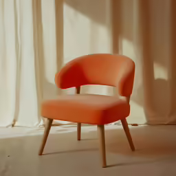 an orange chair with wooden legs in front of a curtain