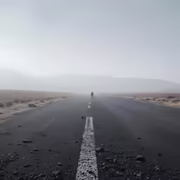 a lone person standing in the middle of an empty road